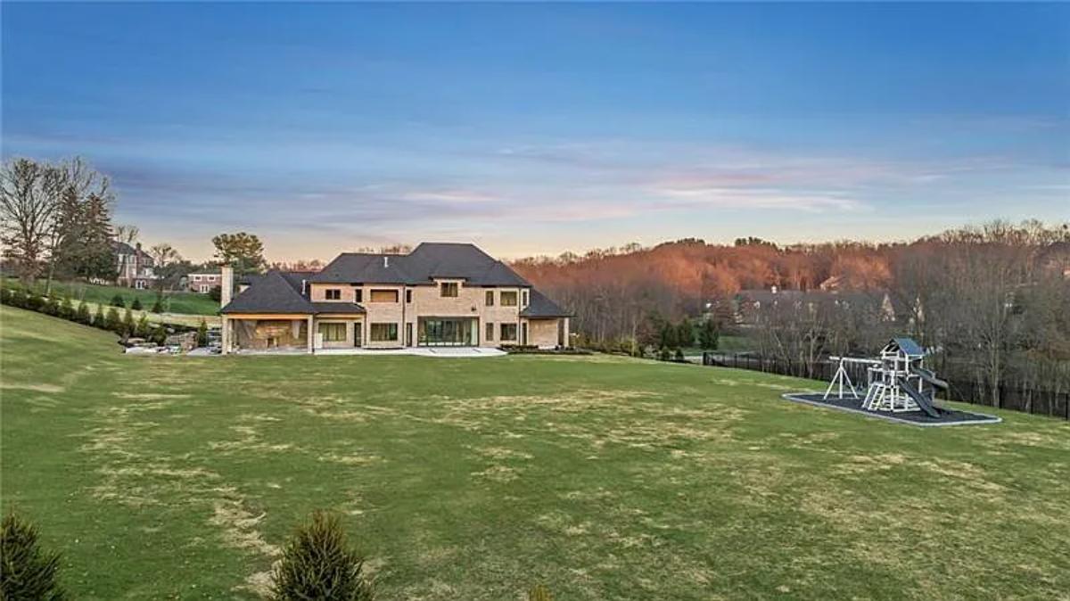 Rear view of the mansion with a large green lawn.