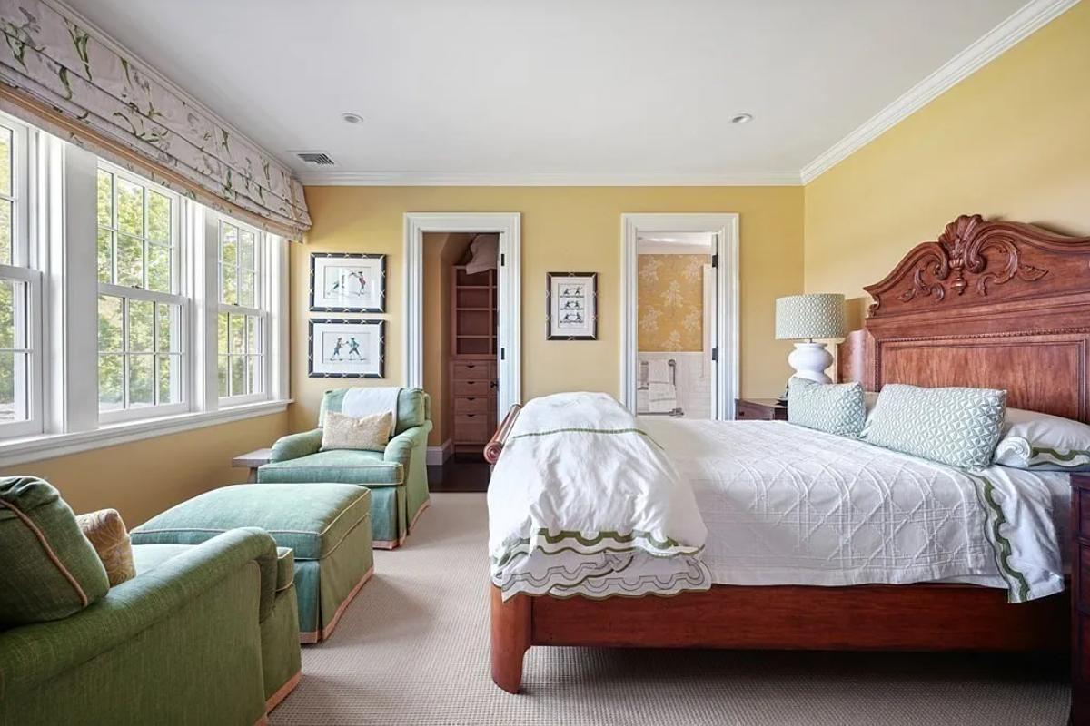 Bedroom with a large bed, couches and carpet flooring.