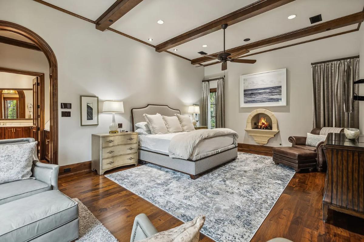 Bedroom with a large bed, a fireplace and hardwood floors.