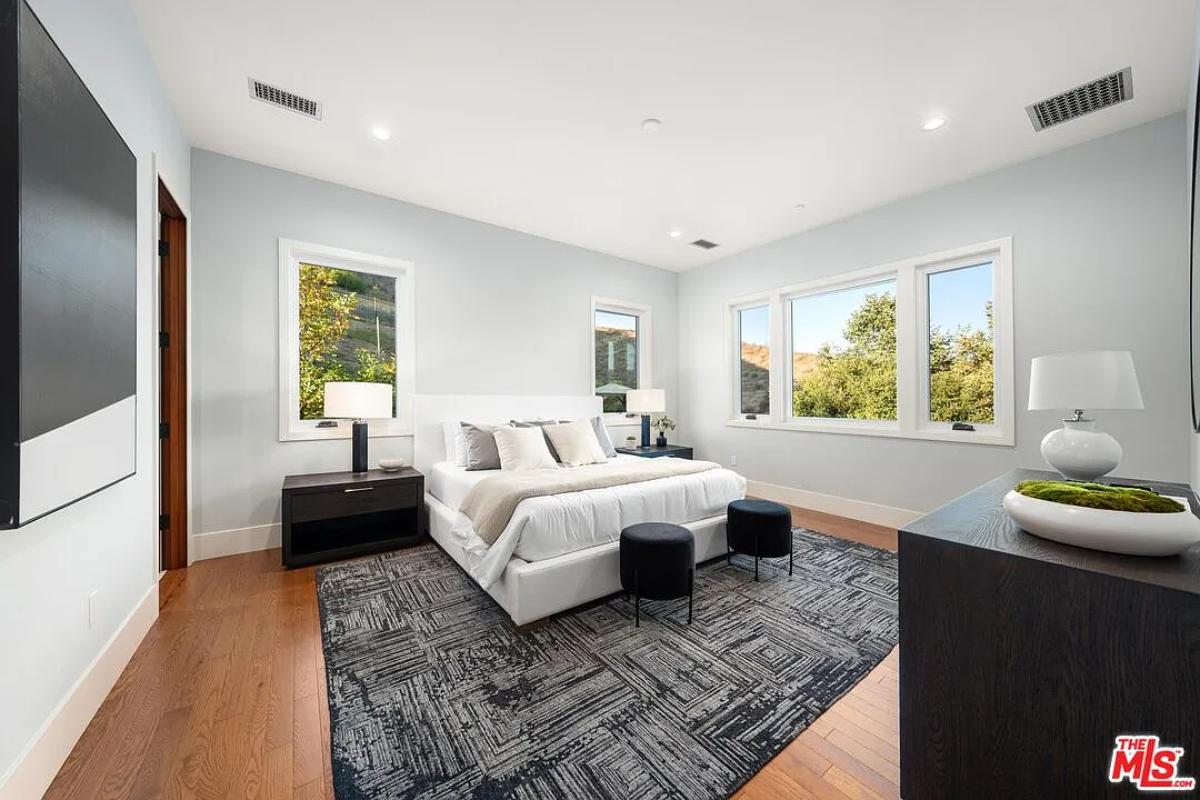 Bedroom with a large bed, glass windows and hardwood floors.