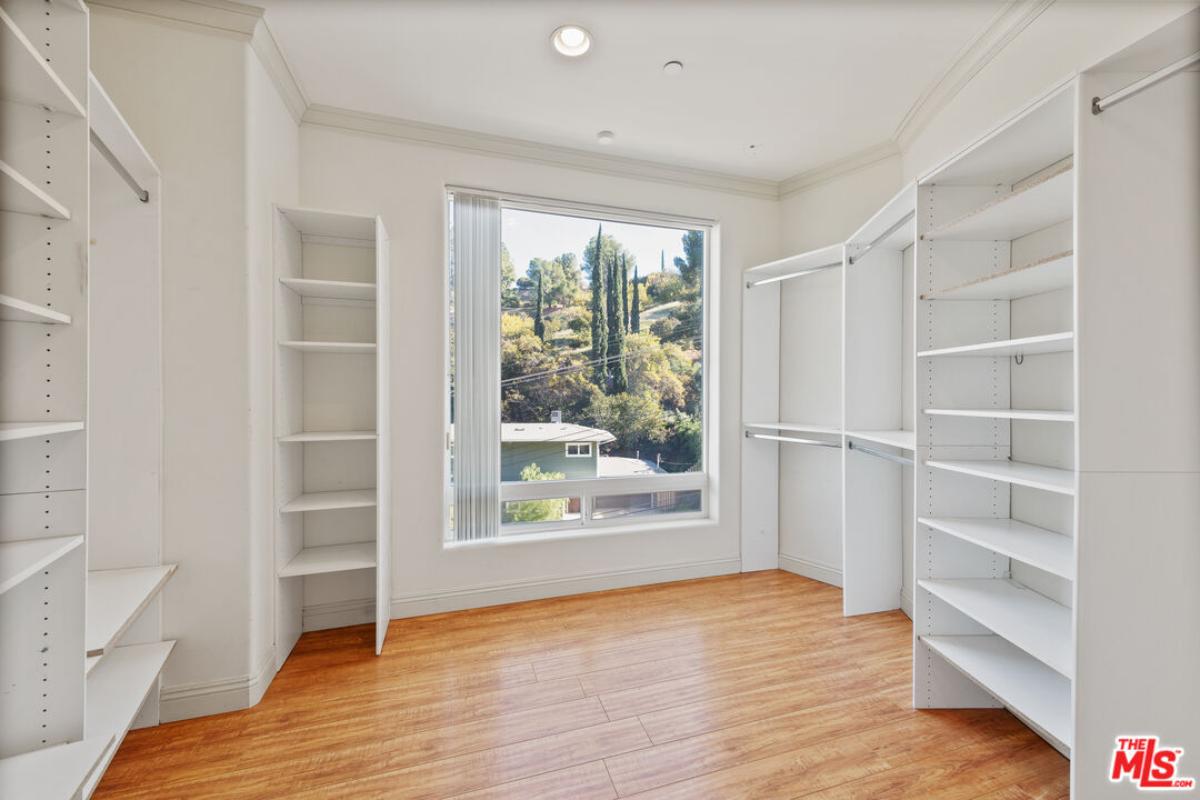 Walk-in closet with shelves and hardwood flooring.