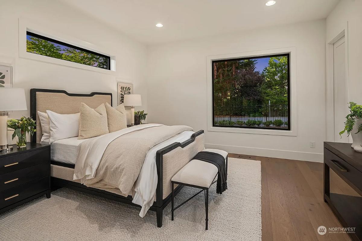 Bedroom with a large bed, glass windows and hardwood floors.