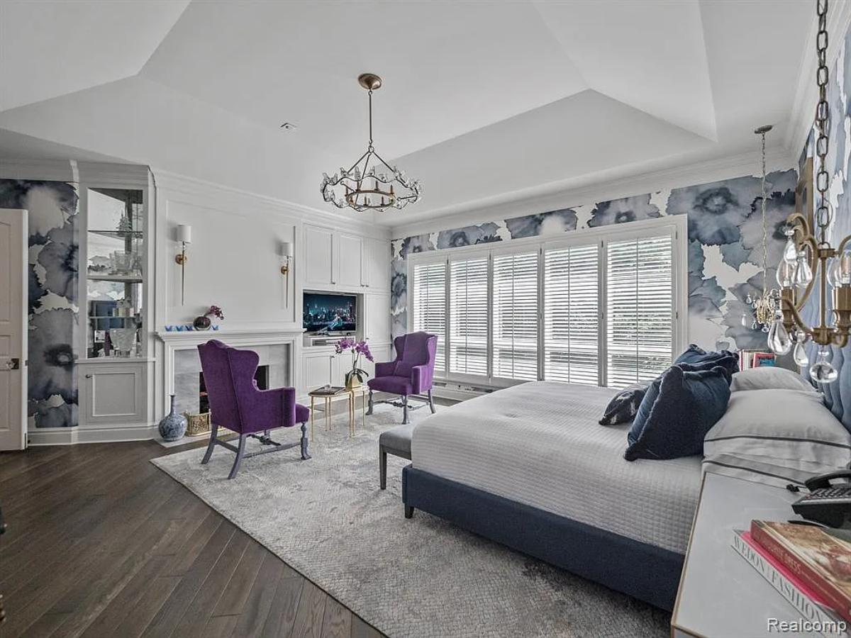 Bedroom with a large bed, a fireplace and hardwood floors.
