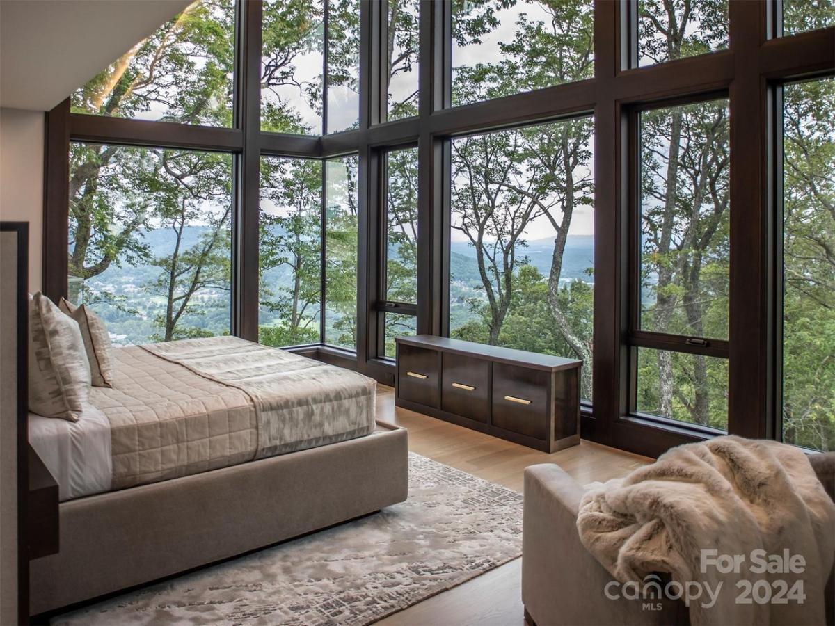 Bedroom with glass walls and mountain views.