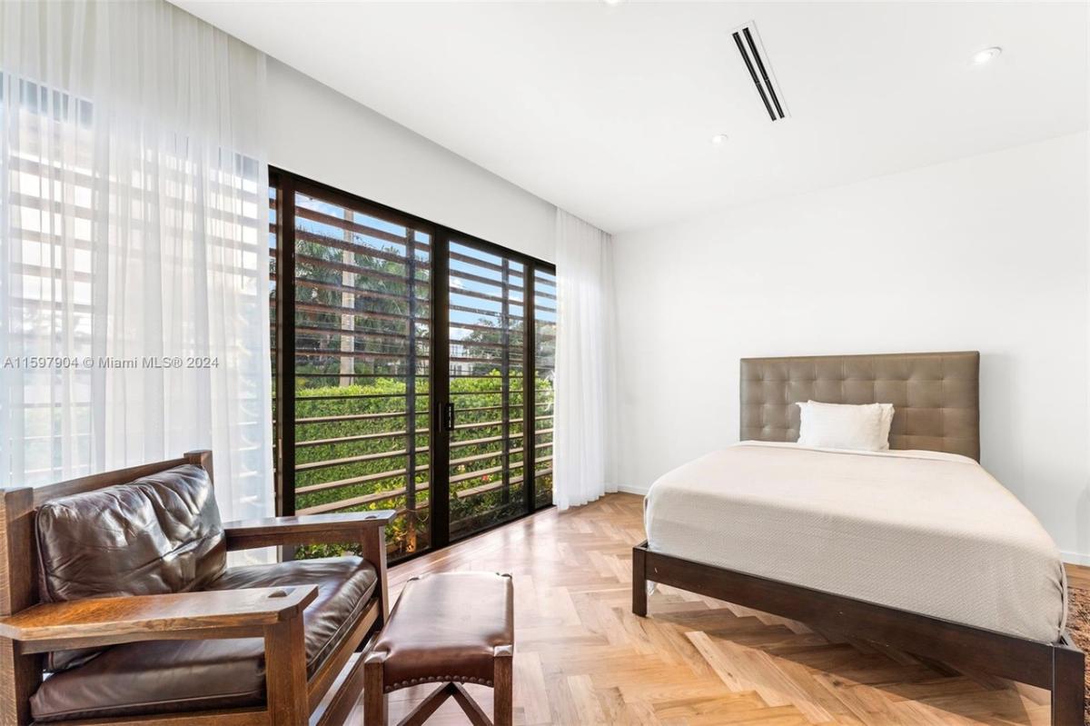 Bedroom with a large bed, sliding glass doors and hardwood floors.