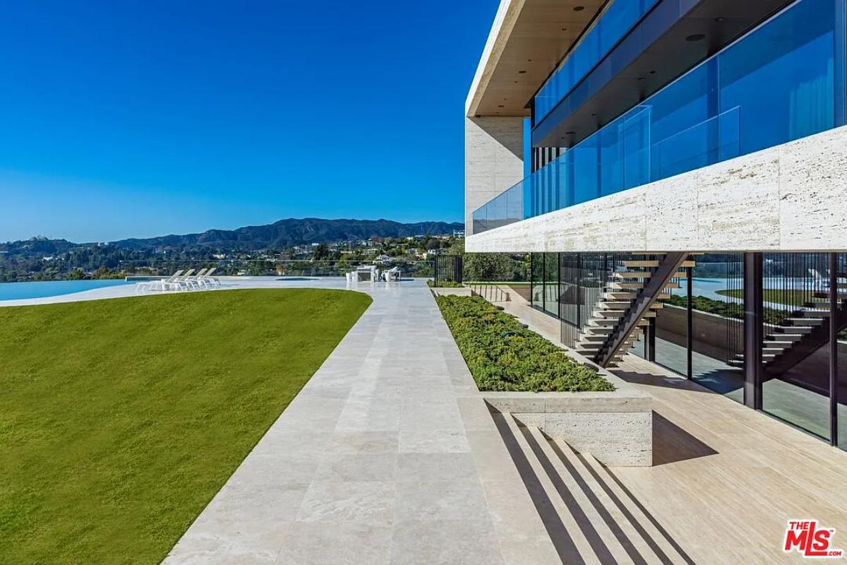 Backyard of the mansion with a pool and a large green lawn.