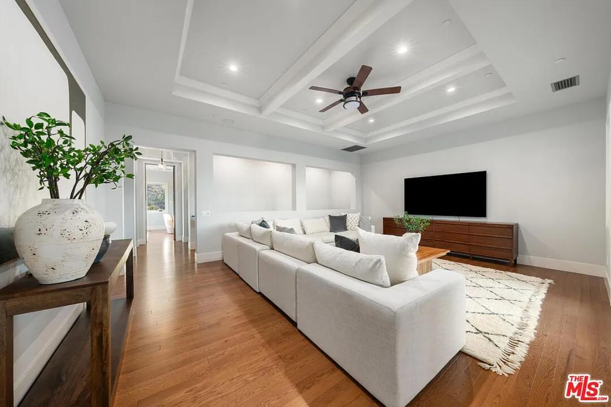 Family room with couches, TV and hardwood floors.
