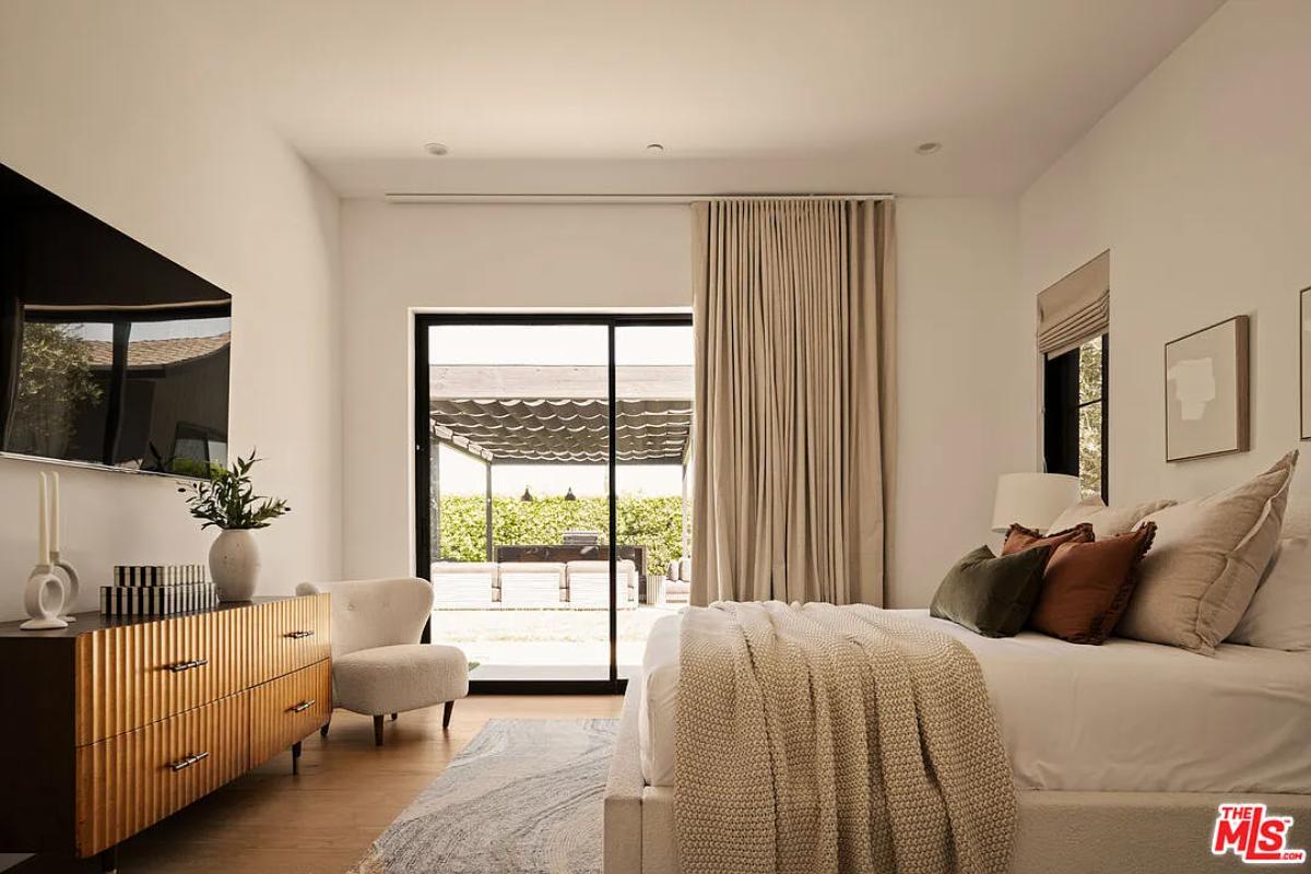 Bedroom with a large bed, sliding glass doors and hardwood floors.