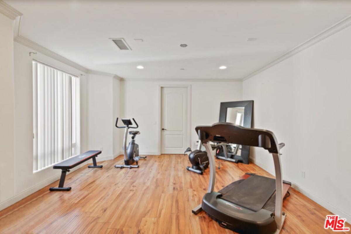 Home gym with hardwood flooring and workout equipment.