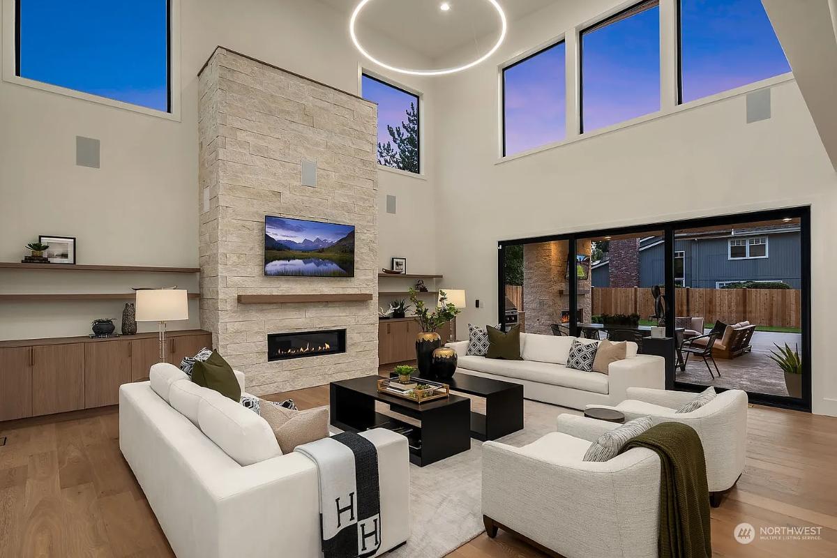 Living room with couches, high ceilings and a fireplace.