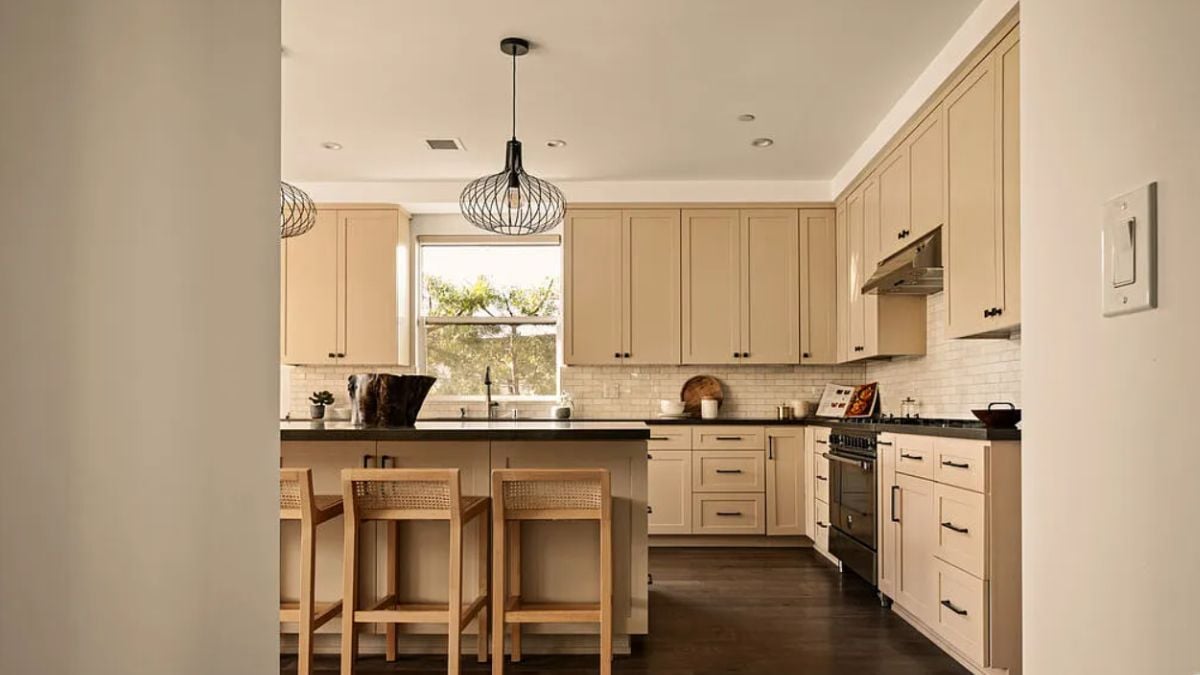 A kitchen with a center island, chairs, countertops, cabinets, and kitchen appliances.