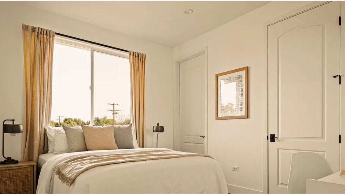 A bedroom with a bed, a window, and a nightstand.