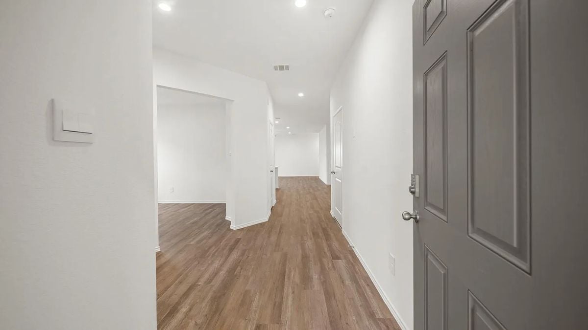 A foyer with a wooden floor, white walls, and a white ceiling.