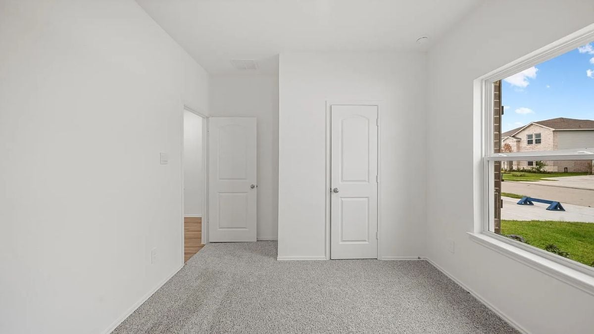 A bedroom with a bed, window, white walls, and a white ceiling.