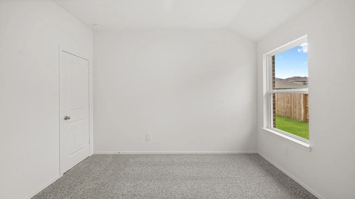 A bedroom with a bed, window, white walls, and a white ceiling.