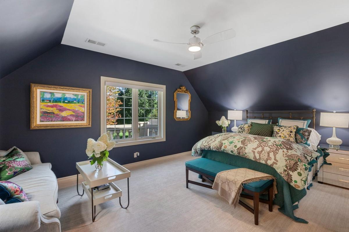 Bedroom with a large bed, a couch and carpet flooring.
