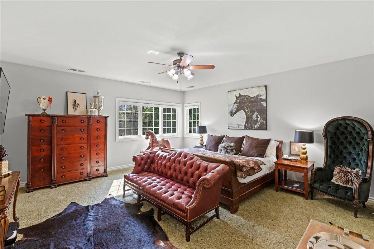 Bedroom with a large bed, a couch and carpet flooring.