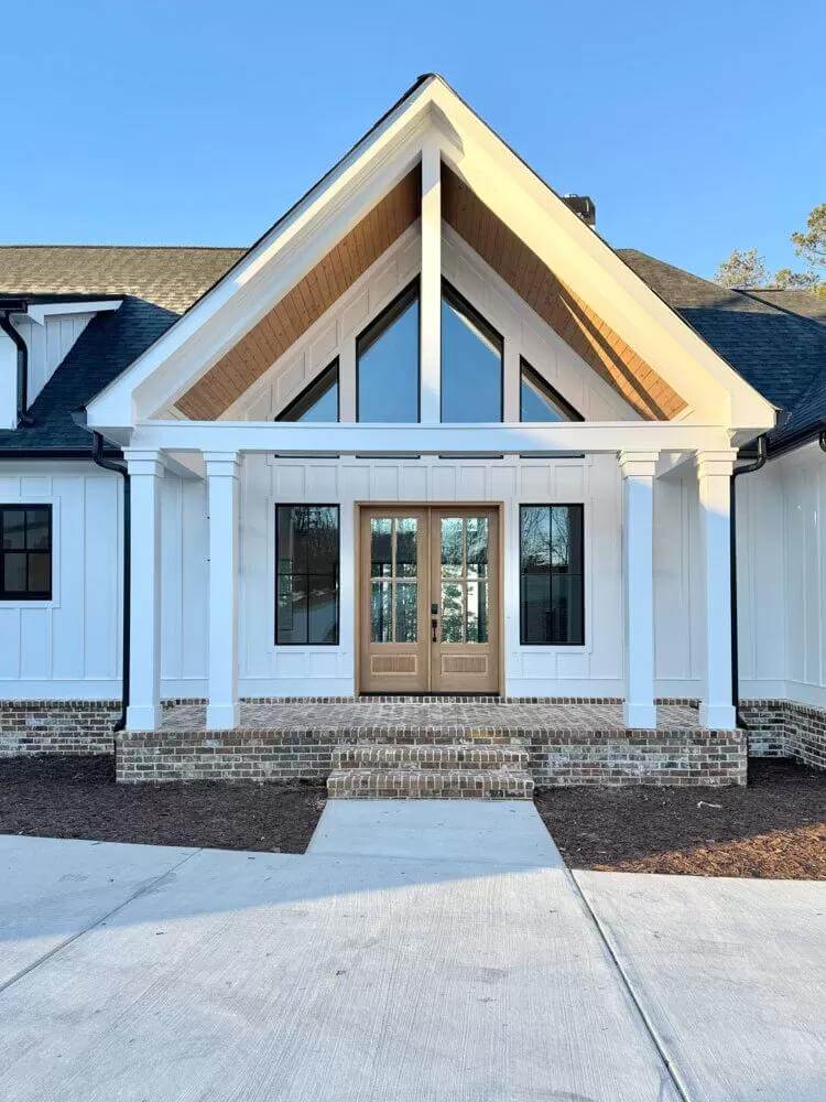 Entry porch with a French front door and a gabled roof supported by white pillars.