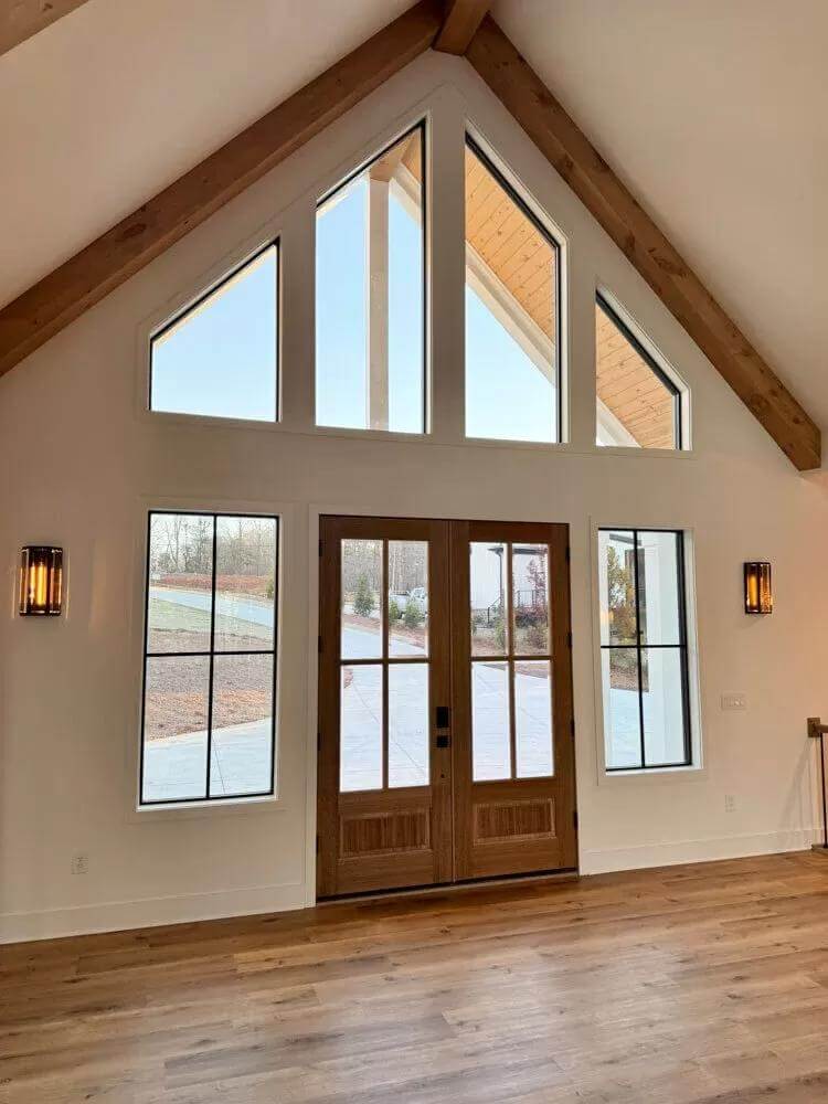 Foyer with a French front door and a cathedral ceiling lined by exposed beams.