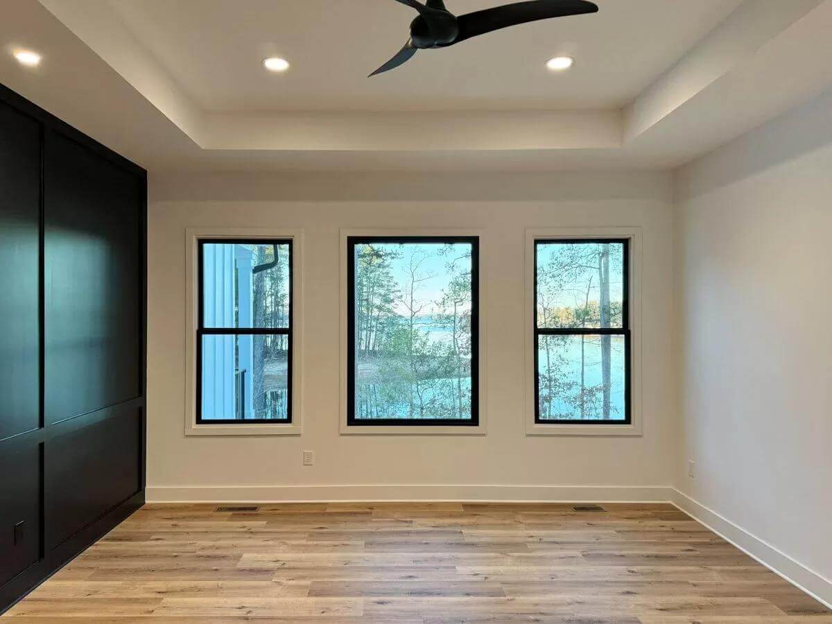 Primary bedroom with a tray ceiling and a black paneled accent wall.