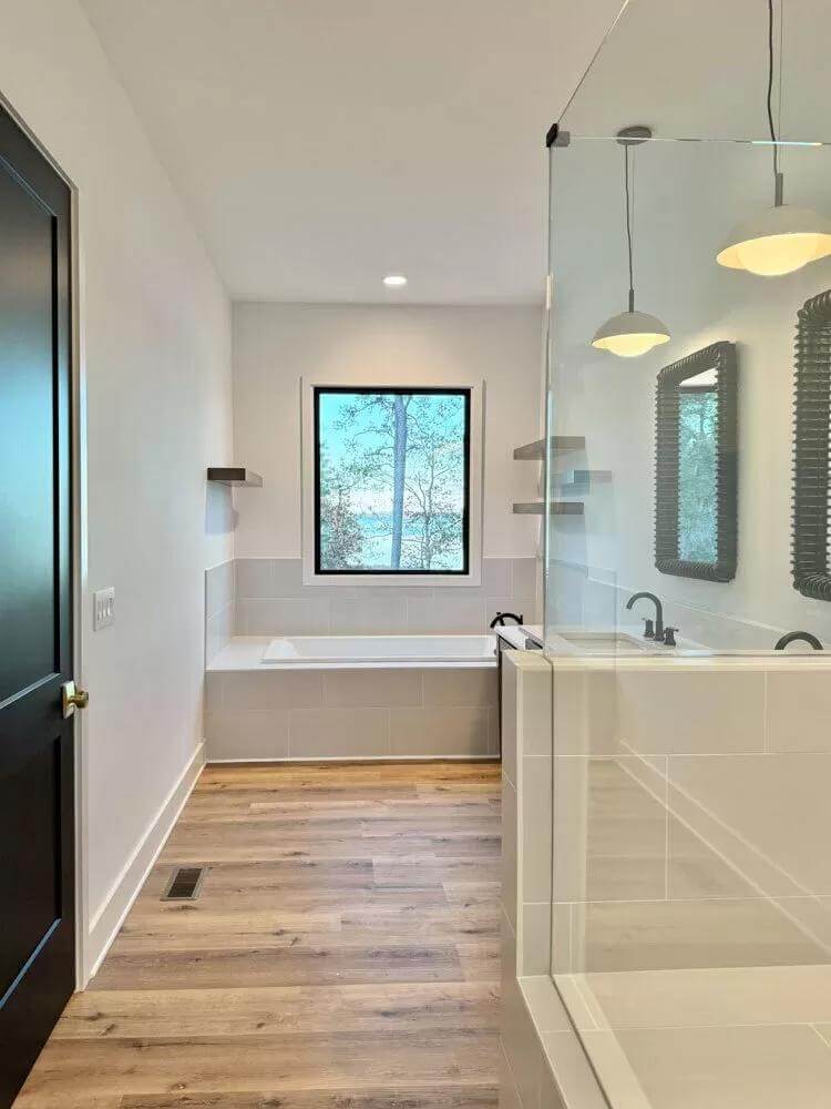 Primary bathroom with a glass-enclosed shower and a bathtub under the picture window.