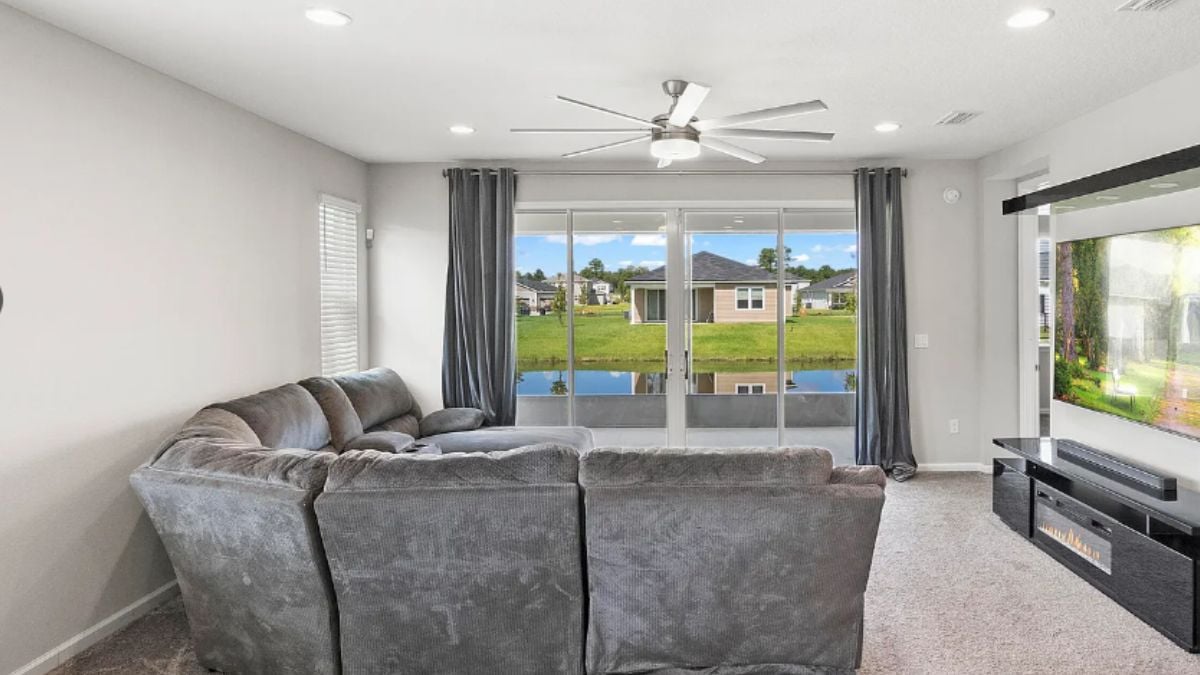 A family room with a ceiling fan, a window, a TV, and a couch.