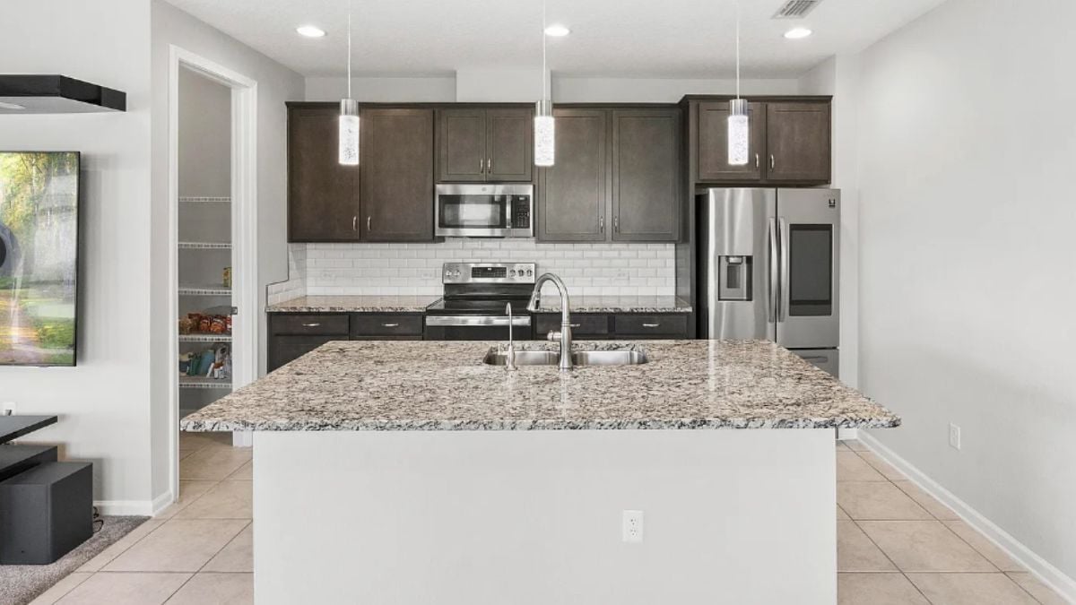 A kitchen with a center island, a sink, cabinets, and kitchen appliances.