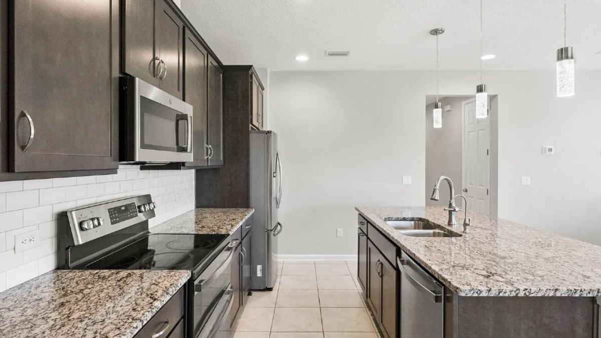 A kitchen with a center island, a sink, cabinets, and kitchen appliances.