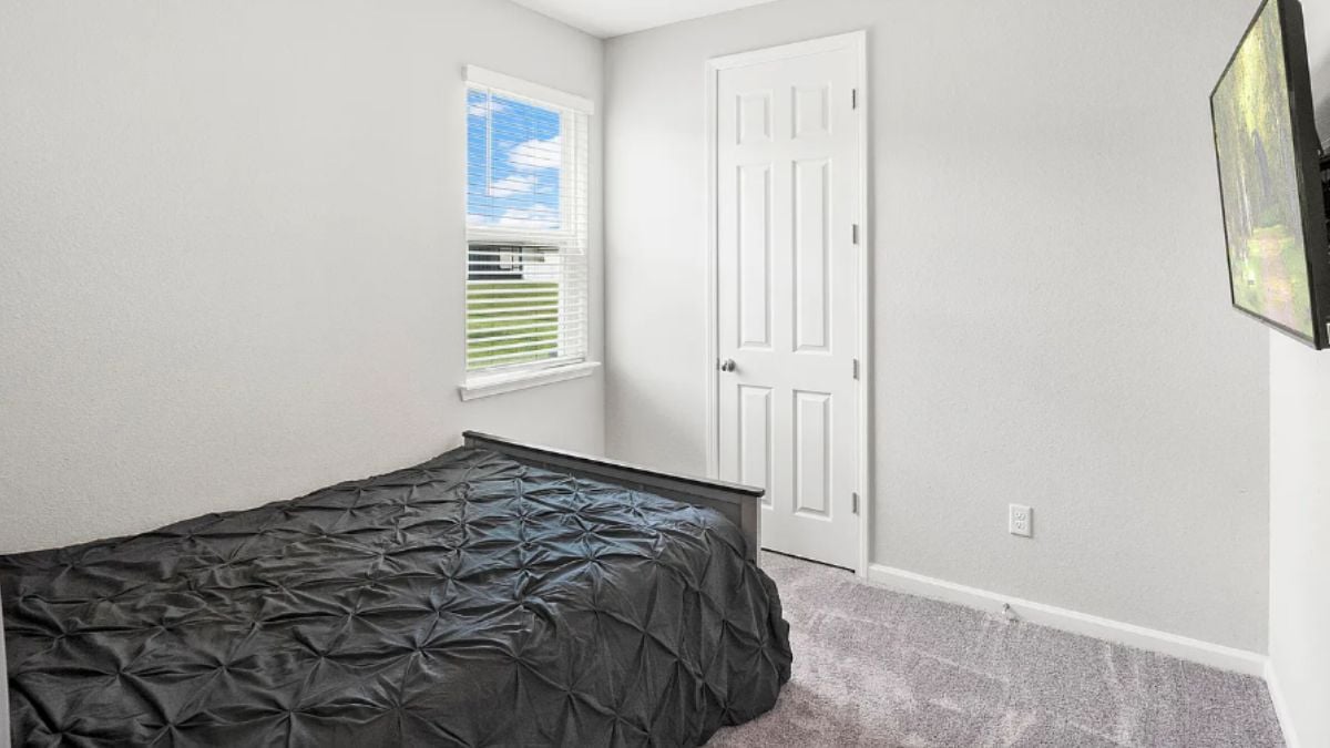 A bedroom with a bed, a window, and a TV.