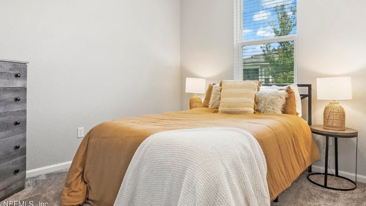 A bedroom with a bed, a window, a nightstand, and a cabinet.