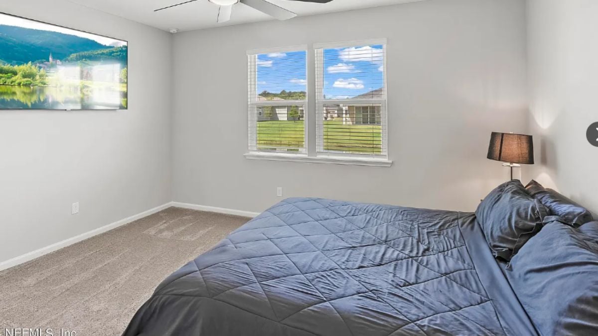 A bedroom with a bed, a window, a ceiling fan, TV and a nightstand.