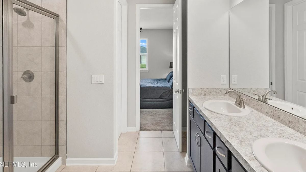 A bathroom with a vanity and a shower room.