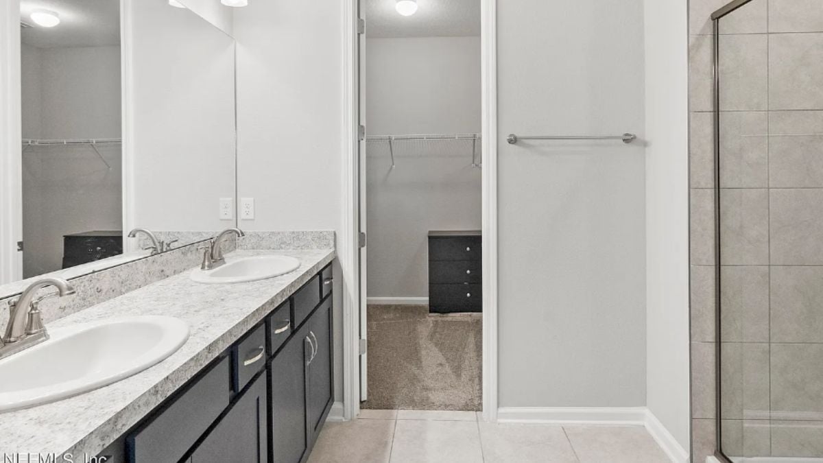 A bathroom with a vanity and a shower room.