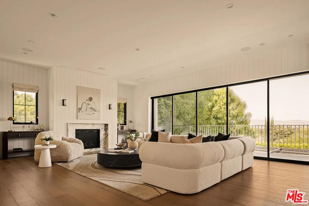 Living room with couches, glass walls and a fireplace.