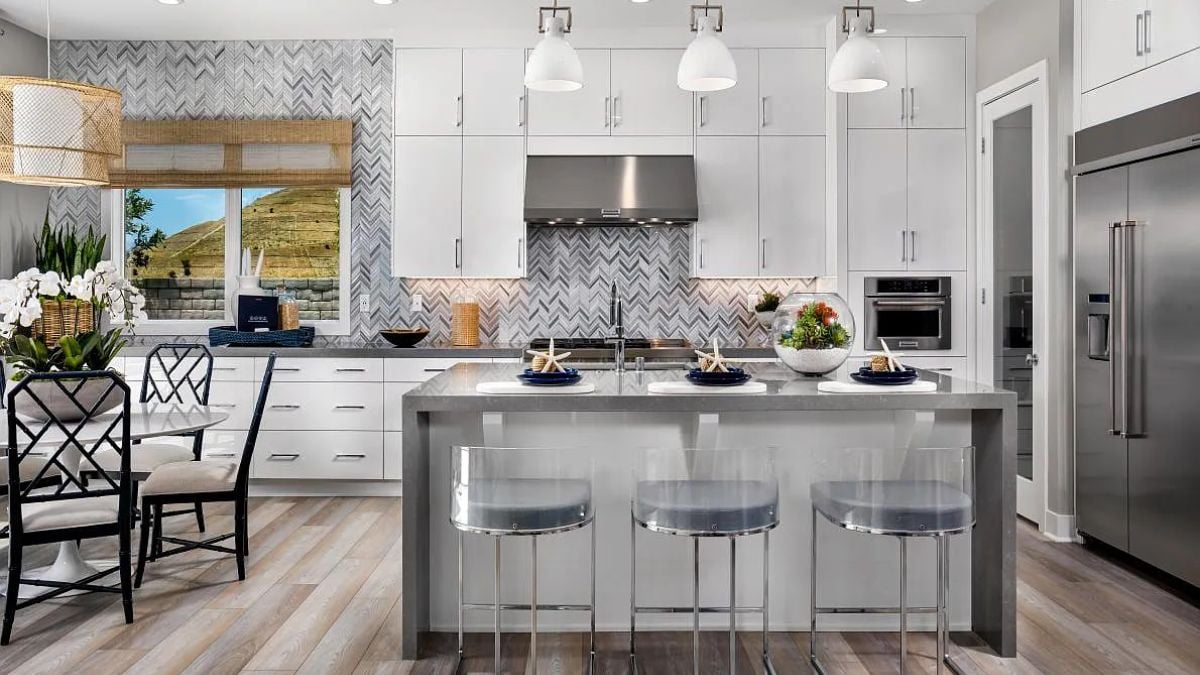 A kitchen with countertops, stools, cabinets, kitchen appliances, and a round table surrounded by chairs.