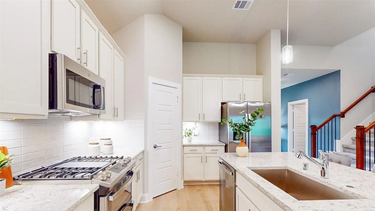 A kitchen with a countertop, sink, cabinets, and kitchen appliances.