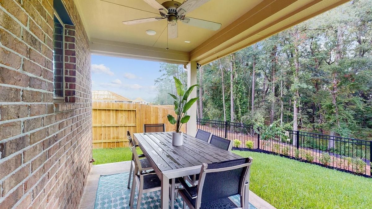 A porch with a ceiling fan and a table surrounded by chairs.