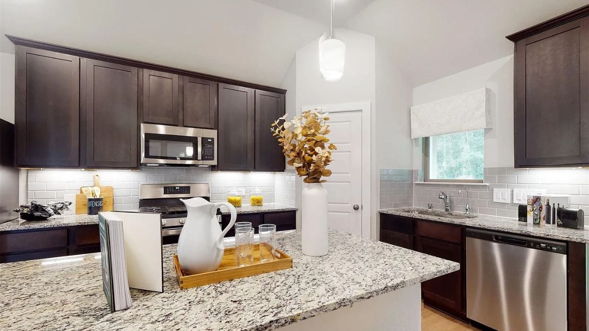 A kitchen with countertops, cabinets, a sink, and kitchen appliances.