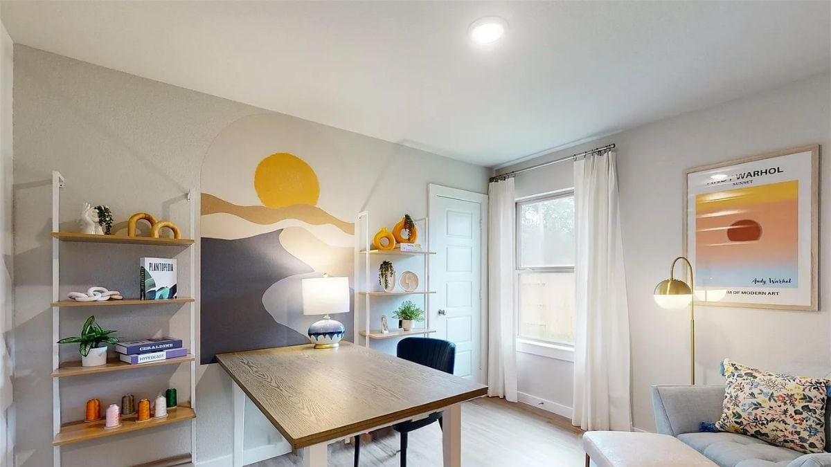 A home office with shelves, a painting, a couch, a desk, and a chair.
