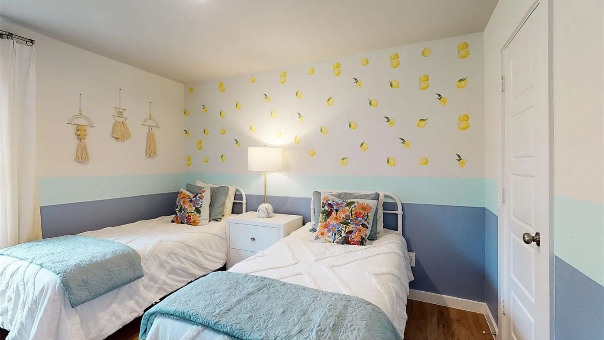 A bedroom with two beds, painted walls, and a nightstand.