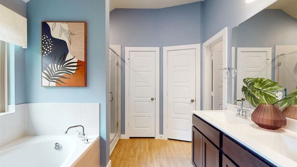A bathroom with a vanity, a mirror, and a bathtub.