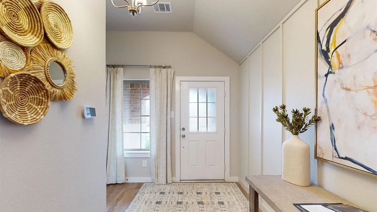 A foyer with a rug, desk, and painting.