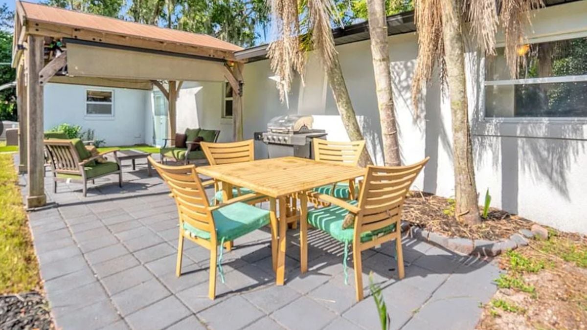 A patio with tables surrounded by chairs.
