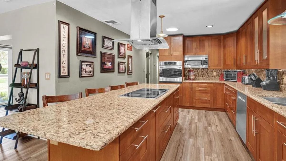 A kitchen with countertops, chairs, a sink, cabinets, and kitchen appliances.
