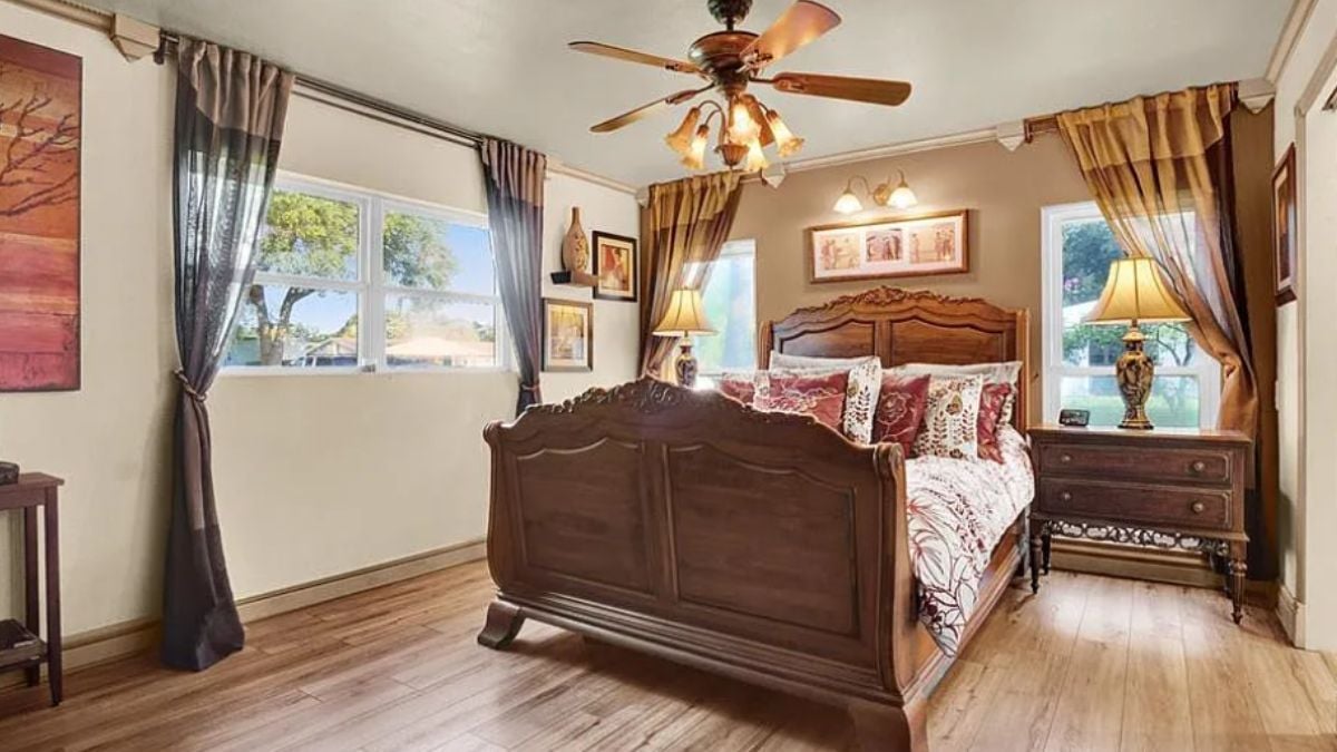 A bedroom with a bed, windows, a ceiling fan, and a nightstand.