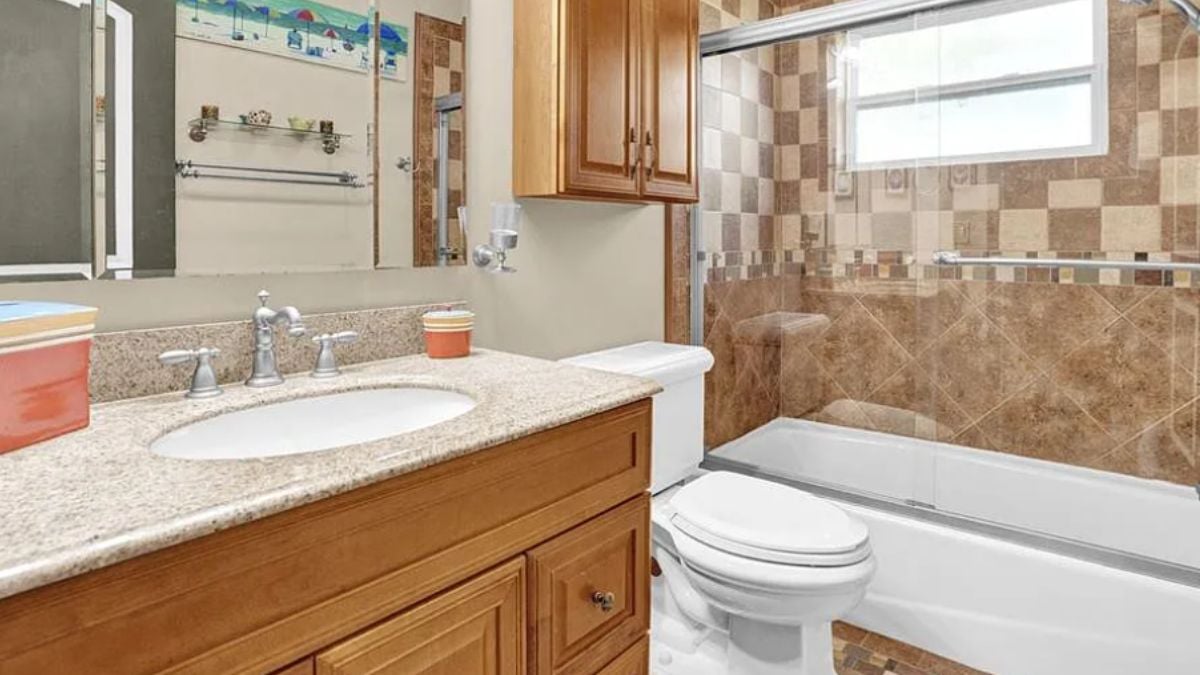 A bathroom with a vanity, a mirror, a bathtub, and a toilet.