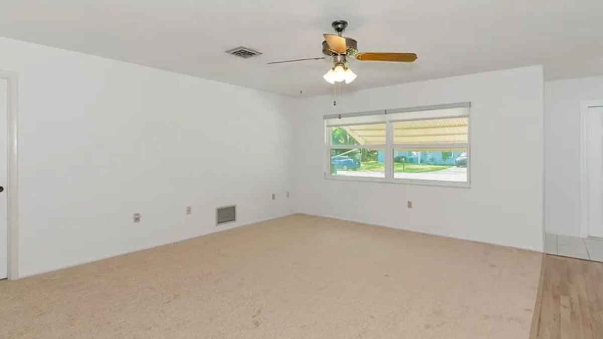 A living room with a window and a ceiling fan.