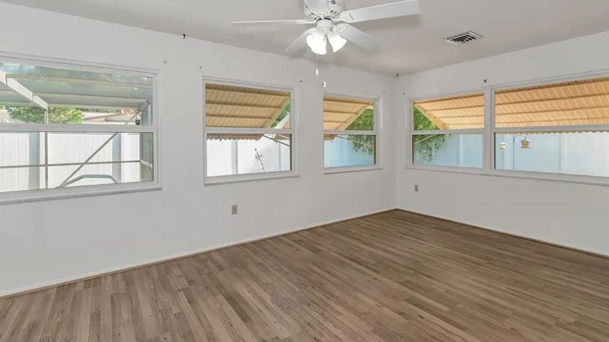 A family room with windows and a ceiling fan.