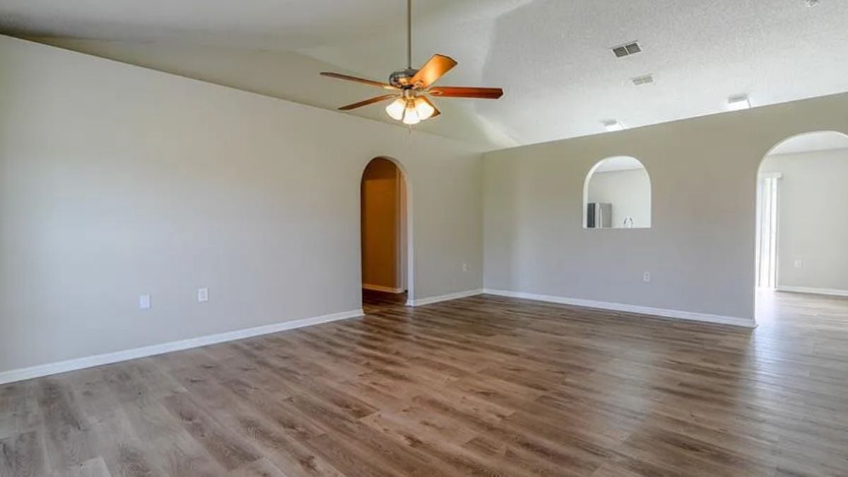 A living room with a wooden floor and a ceiling fan.