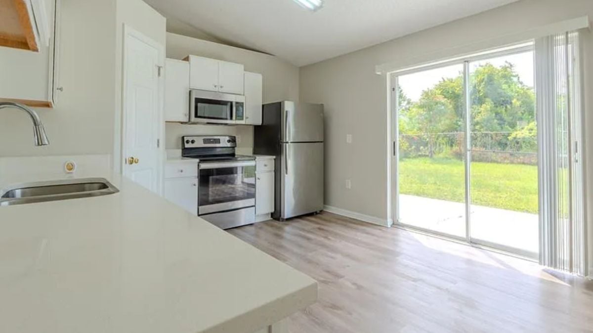 A kitchen with a countertop, a sink, cabinets, and kitchen appliances.